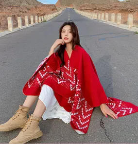 Châle poncho en jacquard rouge avec motif blanc présenté dans un cadre de voyage