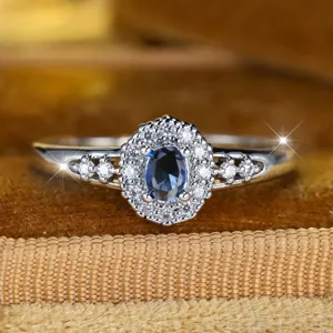 Eleganter Ring mit ovalem blauem Saphir-Zirkon, funkelndem doppeltem Halo und hohlem Banddesign
