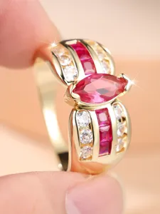 Primer plano de anillo de oro con piedra marquise rosa y roja