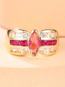 Detalle macro de anillo de oro con gema magenta marquesa y piedras laterales baguette
