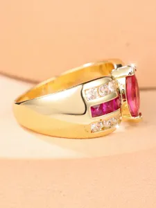 Primer plano de un anillo de oro de lujo con una piedra roja rubí y gemas laterales.
