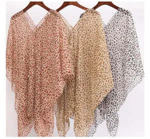 Leopard print sheer bikini cover-ups in three colors hanging on wooden hangers for beach