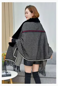 Vista detallada de un poncho de punto grueso con estampado de pata de gallo y flecos.