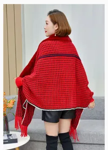 Primer plano detallado de un acogedor poncho de punto de pata de gallo rojo y negro con flecos