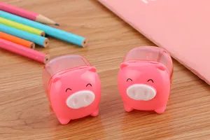 Detailed view of cute pink pig-shaped pencil sharpeners on a wooden desk with pencils