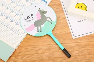 Close-up of a cute cartoon unicorn fan-shaped ballpoint pen displayed on a wooden desk