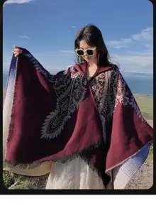 Detail of burgundy hooded cashmere-like poncho with ethnic pattern and fringe edges