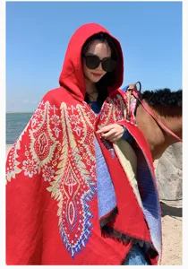 Close-up of a red hooded knit poncho with ethnic floral patterns in an outdoor setting