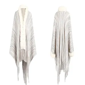 Detailed view of women's grey knitted shawl featuring white faux fur collar and fringe trim