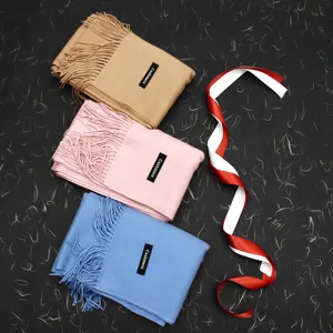 Detailansicht von drei weichen Schals in Rosa, Blau und Camel mit Fransenquasten