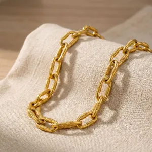 Primo piano di una collana a maglie grosse dorate con trama a costine elegante
