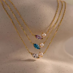 Detail view of marquise-cut zircon and pearl pendants on delicate gold chains