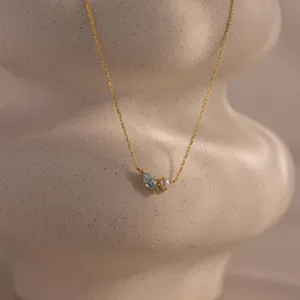 Close-up of gold titanium steel necklace with blue marquise zircon and pearl.