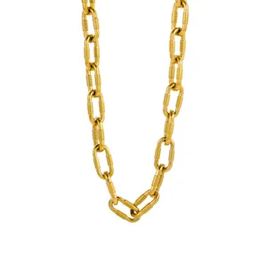 Dettaglio ravvicinato di una collana a catena d'oro minimalista con maglie in metallo testurizzato