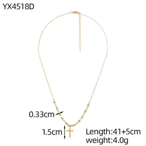 Detail view of handmade beaded necklace with gold cross pendant and green beads