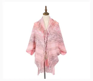 Front view of a stylish pink knit poncho shawl featuring long decorative fringe detail