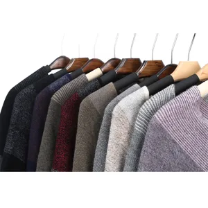 Rangée de ponchos tricotés colorés sur cintres en bois pour une chaleur automnale douce.
