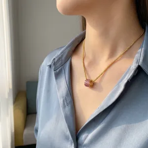 Gedetailleerde weergave van een gouden titanium ketting met robijnrode cilinderhanger op model.