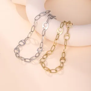 Macro detail of vintage-style gold and silver chain necklaces on a minimalist display prop