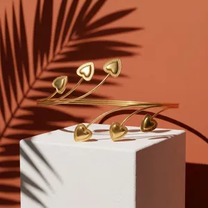 Elegant gold heart geometric arm cuff displayed on a white block with tropical shadows