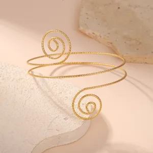 Vista macro dettagliata di un bracciale da braccio geometrico a spirale dorata su pietra grezza