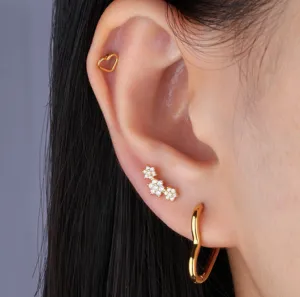 Close-up detail of various titanium steel gold earrings with floral and heart motifs.