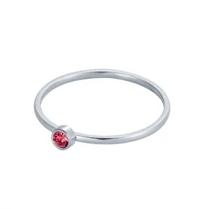 Gros plan d'une bague minimaliste en argent sertie d'une petite pierre de naissance rose.