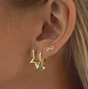 Macro view of gold-plated star and infinity earring set styled on a female model ear
