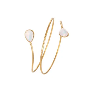 Detailed macro view of golden spiral arm cuff featuring iridescent pear-shaped stones