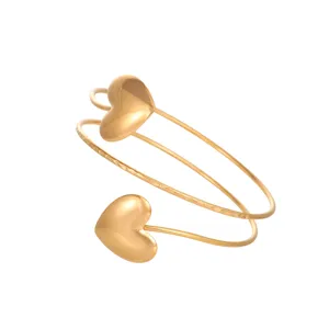 Close-up detail of a golden heart-shaped geometric arm cuff with hammered texture
