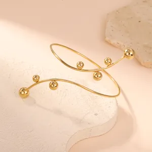 Vista dettagliata di un elegante bracciale geometrico dorato con accenti sferici