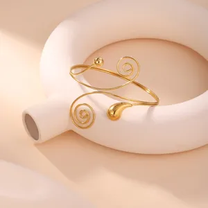 Dettaglio di un elegante bracciale geometrico dorato a spirale su base ceramica