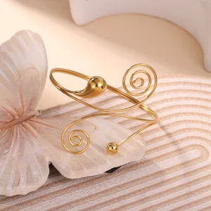Primo piano di un elegante bracciale da braccio a spirale dorato con goccia lucida
