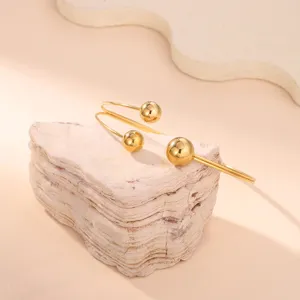 Dettaglio di un bracciale da braccio geometrico dorato con sfere lucide su pietra