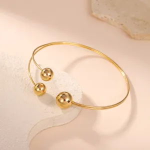 Primo piano di un elegante bracciale da braccio dorato con tre sfere di metallo.