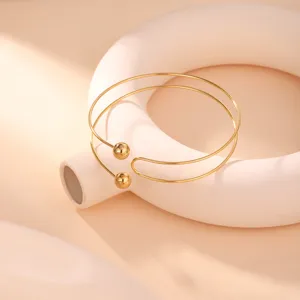 Dettaglio ravvicinato di un elegante bracciale geometrico dorato con sfere minimaliste