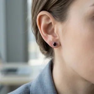 Detailed close-up showing a small red zircon stud earring worn on a female ear lobe