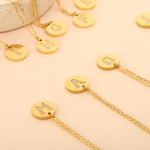 Detaillierte Nahaufnahme goldener Titanstahl-Halsketten mit glitzernden Buchstabenanhängern
