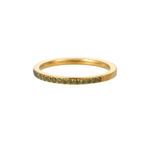 Detalle de un anillo de banda dorado engastado con circonitas verde oliva brillantes