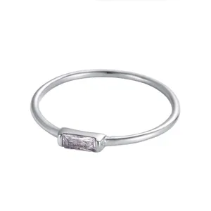 Dettaglio di un anello d'argento minimalista con una pietra di zircone rettangolare.