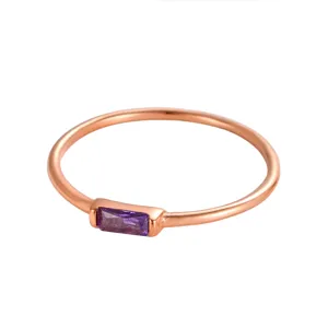 Primo piano di un anello minimalista in oro rosa con pietra preziosa viola rettangolare