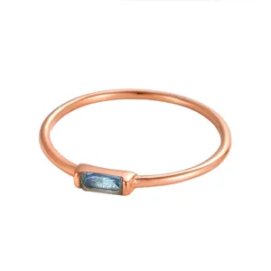 Primo piano di un anello in oro rosa con una pietra preziosa blu rettangolare