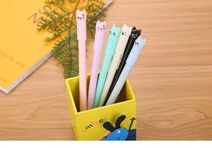 Detailed close-up of cute cartoon cat head gel pens in various pastel colors in a holder