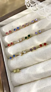Detailweergave van minimalistische ronde oorknopjes met kleurrijke strass-steentjes