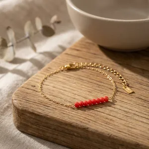 Close-up of a minimalist gold chain bracelet featuring vibrant red natural stone beads