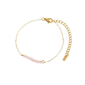 Close-up of a thin gold chain bracelet featuring faceted pink natural stone beads