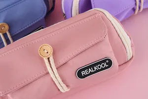 Nahaufnahme eines rosa Segeltuch-Federmäppchens mit Knopfverschluss und Logo-Detail
