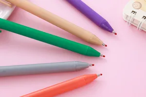 Close-up of Morandi color gel pen tips with protective red beads on pink background