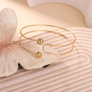 Dettaglio di un elegante bracciale geometrico dorato per il braccio con sfere metalliche