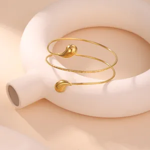 Vista ravvicinata di un bracciale a spirale dorato con trama martellata e gocce